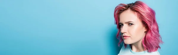Jeune femme tendue aux cheveux roses sur fond bleu, plan panoramique — Photo de stock