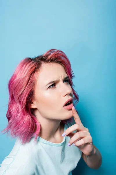 Jovem mulher pensativa com cabelo rosa no fundo azul — Fotografia de Stock