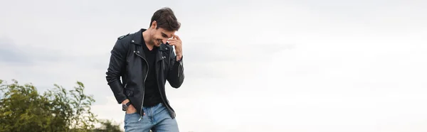 Panoramic shot of man in leather jacket standing outdoors — Stock Photo