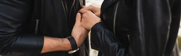 Заголовок сайта молодой пары в кожаных куртках, держащихся за руки на открытом воздухе — стоковое фото