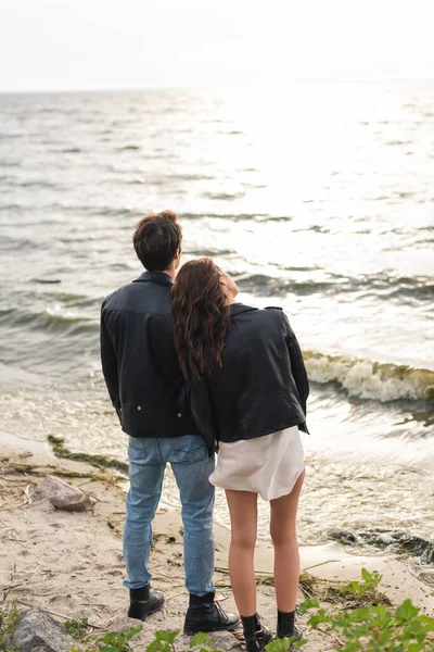 Back view of young couple standing on sandy beach near sea — Stock Photo