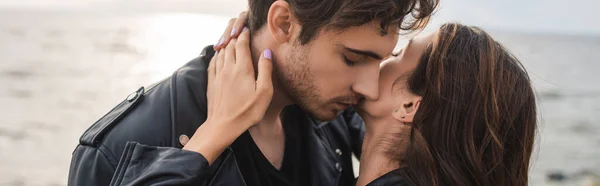 La cosecha horizontal de la mujer que toca el cuello del novio junto al mar - foto de stock