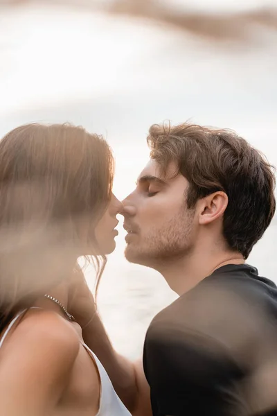 Focus selettivo dell'uomo baciare e toccare la ragazza vicino al mare — Foto stock