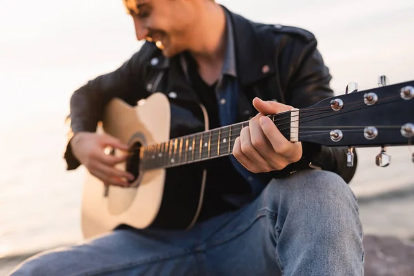 Избирательный фокус человека, играющего на акустической гитаре под открытым небом — стоковое фото