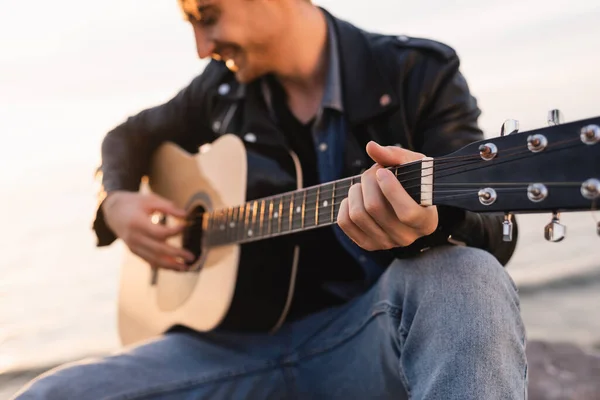 Enfoque selectivo del hombre tocando la guitarra acústica al aire libre - foto de stock