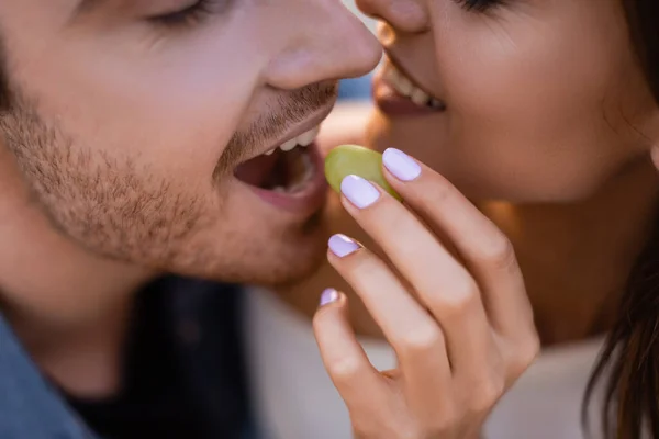 Vista ritagliata della donna che alimenta il fidanzato con uva all'aperto — Foto stock
