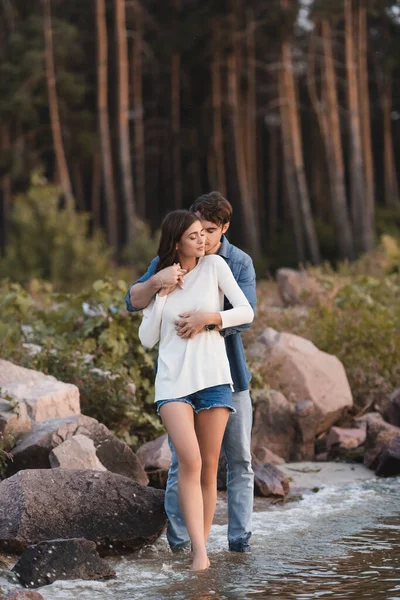 Jovem casal abraçando perto de pedras e mar na praia — Fotografia de Stock