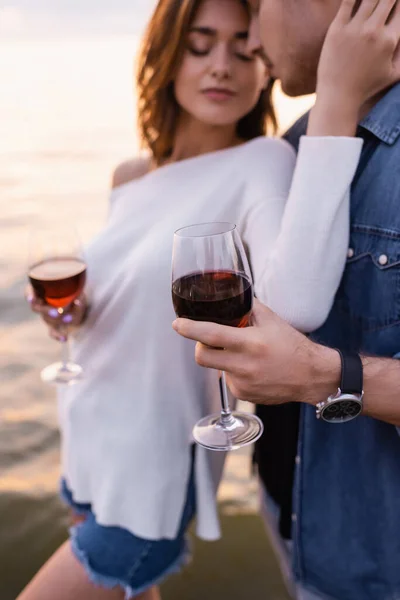 Focus selettivo dell'uomo in possesso di un bicchiere di vino vicino alla fidanzata e al mare — Foto stock