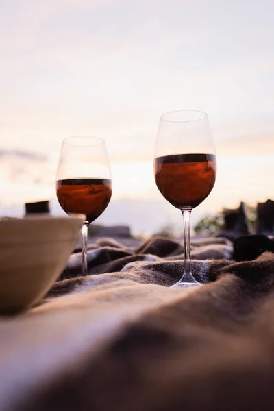 Selective focus of glasses of wine near bowl on blanket outside — Stock Photo