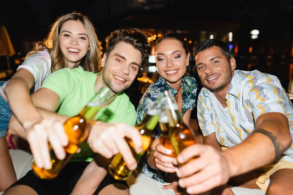 Focus selettivo di giovani amici che si accarezzano di birra all'aperto di notte — Foto stock