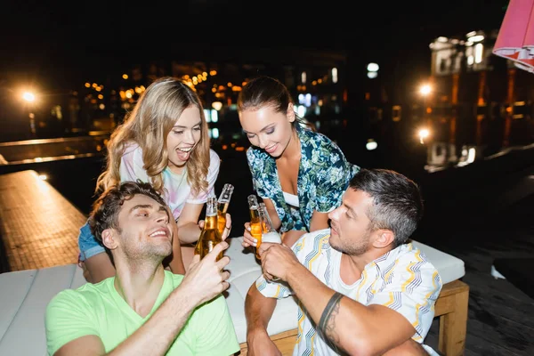 Захоплені молоді пари тримають пляшки пива надворі вночі. — стокове фото