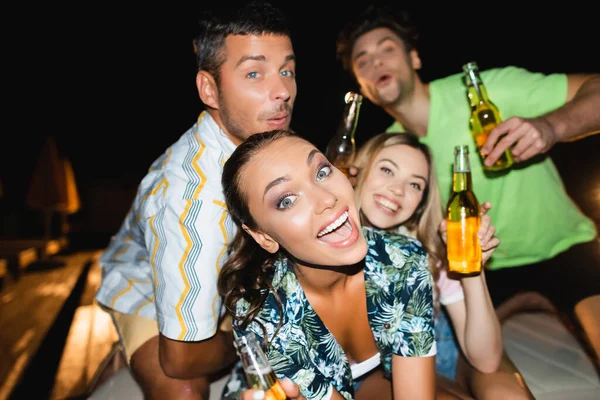 Concentration sélective de la femme regardant la caméra près du petit ami et des amis la nuit — Photo de stock