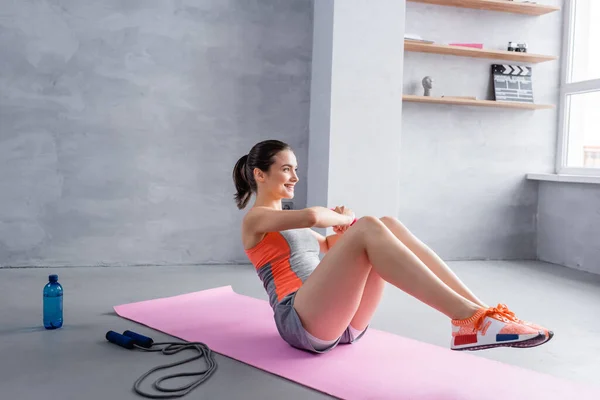 Sportswoman avec jambes dans l'air exercice sur tapis de fitness à la maison — Photo de stock