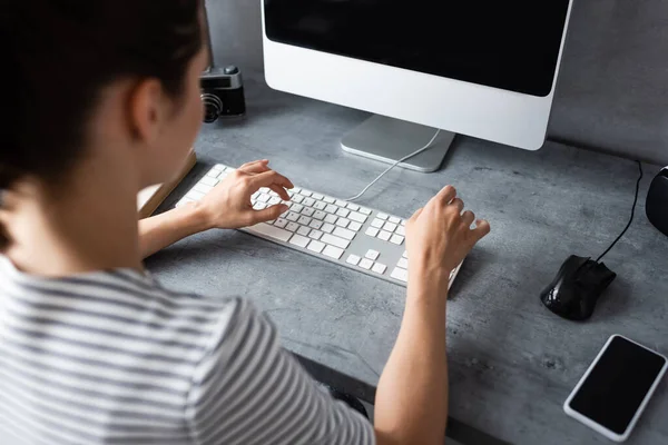 Foco seletivo do freelancer usando o teclado do computador perto do smartphone na mesa em casa — Fotografia de Stock