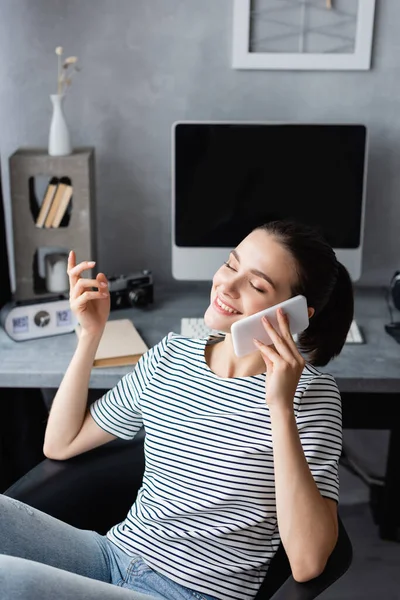 Young teleworker talking on smartphone with closed eyes at home — Stock Photo