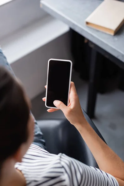 Вид сверху на молодую женщину с помощью смартфона с чистым экраном дома — стоковое фото