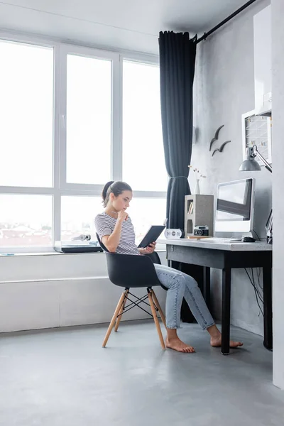 Brünette Freiberuflerin hält Notizbuch in der Nähe des Computers auf dem heimischen Tisch — Stockfoto