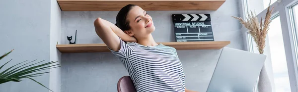 Panoramic shot of freelancer looking at window near laptop at home — Stock Photo