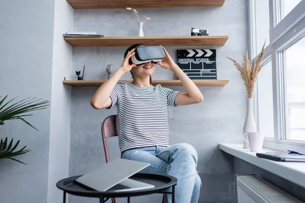 Focus selettivo del libero professionista utilizzando auricolare vr vicino laptop sul tavolino da caffè a casa — Foto stock