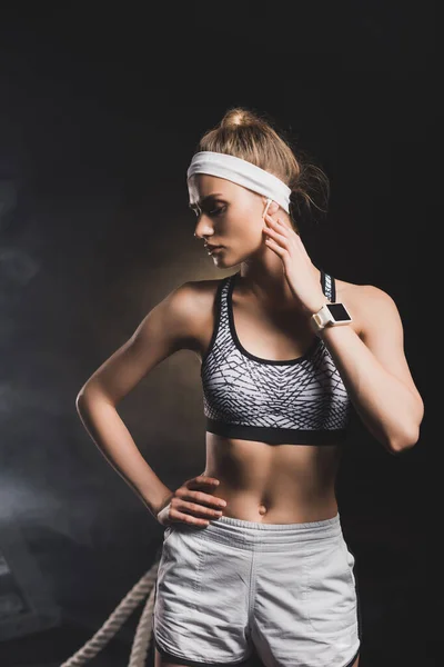 Vue de face de la sportive debout avec la main sur la hanche et regardant loin — Photo de stock