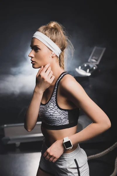 Enfoque selectivo de la deportista con reloj inteligente mirando hacia otro lado en el gimnasio - foto de stock