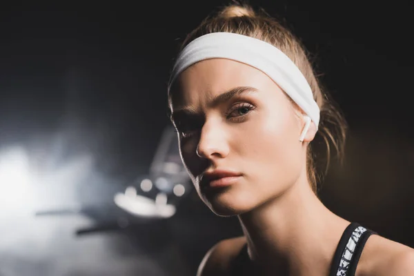Selektive Sicht der Sportlerin mit Kopfhörer auf die Kamera im Fitnessstudio — Stockfoto
