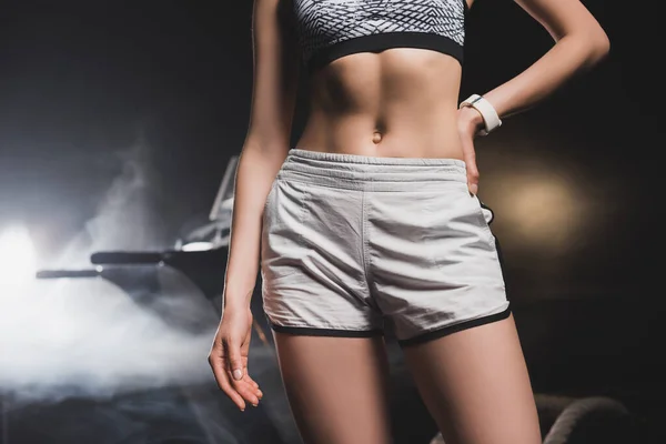 Cropped view of sportswoman standing with hand hip near treadmill in gym — Stock Photo