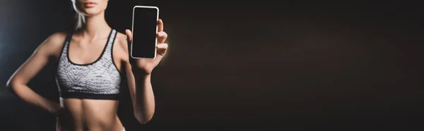 Imagen panorámica de la deportista mostrando el teléfono móvil con pantalla en blanco - foto de stock