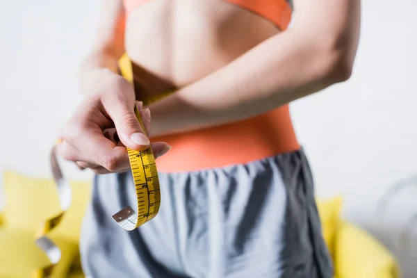 Selective focus of sportswoman with measuring tape at home — Stock Photo