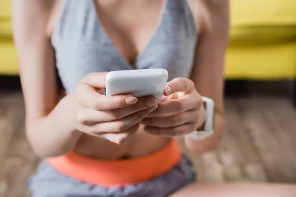 Vista recortada de la deportista sosteniendo el teléfono celular - foto de stock