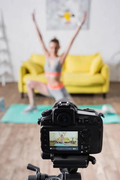 Foco seletivo da jovem esportista exercitando perto da câmera digital no tripé em casa — Fotografia de Stock