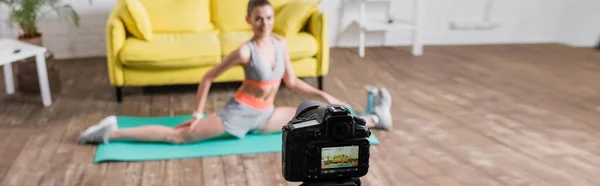 Imagen panorámica de la deportista haciendo split mientras entrena cerca de la cámara digital - foto de stock