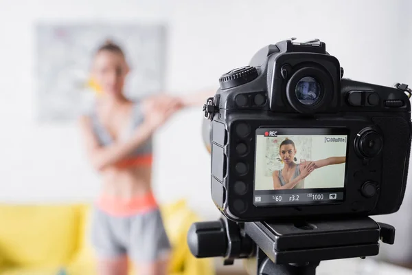 Selective focus of digital camera near sportswoman exercising at home — Stock Photo