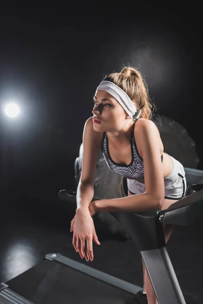 Jeune sportive debout sur un tapis roulant près d'un pneu dans un gymnase — Photo de stock