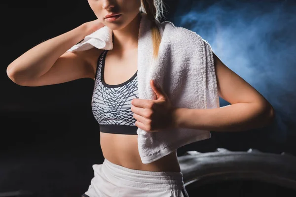 Cropped view of young sportswoman holding towel in sports center with smoke — Stock Photo
