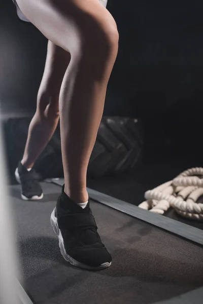 Cropped view of sportswoman running on treadmill in sports center — Stock Photo