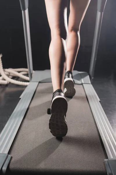 Cropped view of sportswoman running on treadmill in sports center — Stock Photo