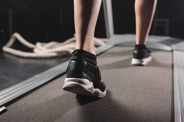 Cropped view of sportswoman running on treadmill in sports center — Stock Photo