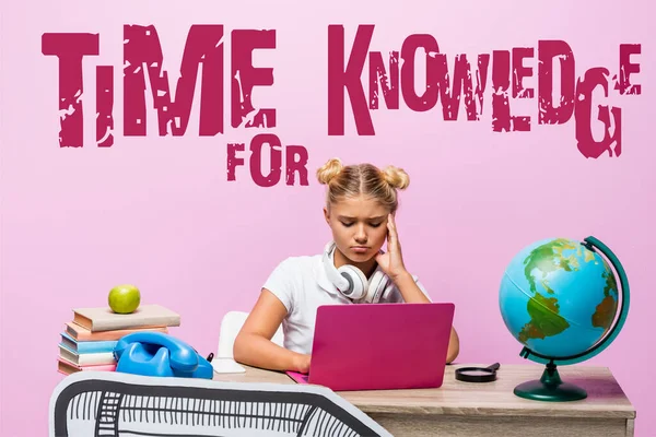 Sad kid in headphones using laptop near globe, books, retro telephone, time for knowledge lettering and paper art on pink — Stock Photo