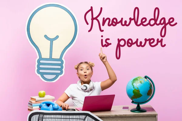Emocionado colegial tener idea cerca de gadgets, ilustraciones de papel y el conocimiento es el poder de letras en el fondo rosa - foto de stock