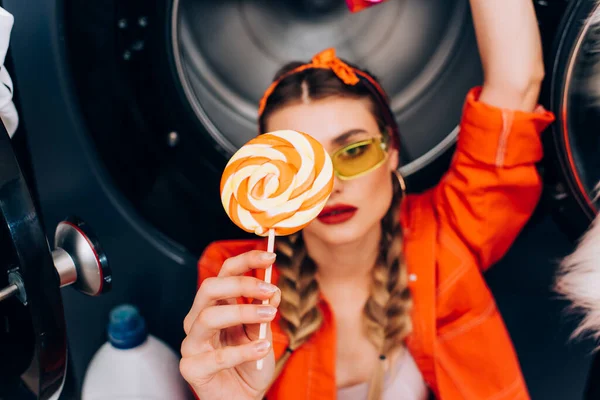 Sweet lollipop in hand of fashionable woman in sunglasses on blurred background — Stock Photo