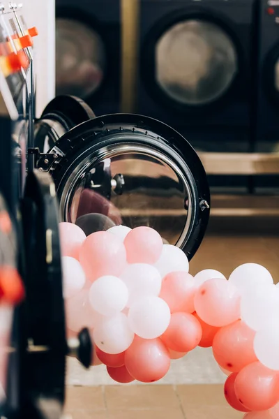 Ballons in der Nähe moderner Waschmaschinen im Waschsalon mit verschwommenem Vordergrund — Stockfoto