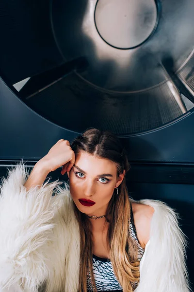 Jeune femme en fausse veste de fourrure regardant la caméra dans la laverie automatique — Photo de stock