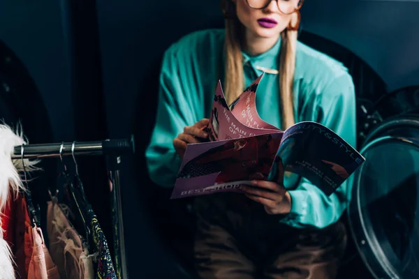 Ausgeschnittene Ansicht einer stilvollen Frau mit Magazin im Waschsalon — Stockfoto