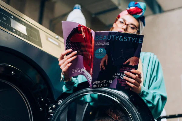 Magazin in den Händen einer verschwommenen und stilvollen Frau im öffentlichen Waschsalon — Stockfoto