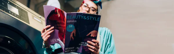 Trendfrau mit Brille und Turban hält Magazin im öffentlichen Waschsalon, Banner — Stockfoto