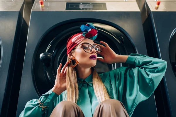 Stylische junge Frau mit Brille und Turban schaut in der Nähe der Waschmaschine weg — Stockfoto