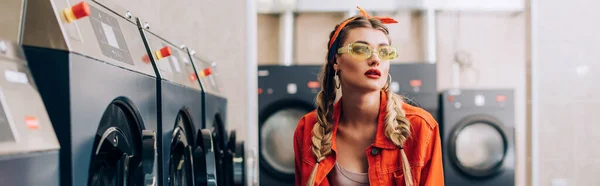 Femme élégante en bandeau et lunettes de soleil dans la laverie automatique moderne, bannière — Photo de stock