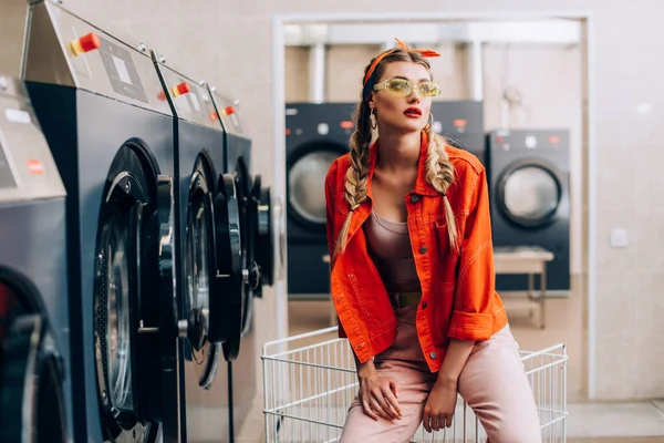 Femme élégante en bandeau et lunettes de soleil dans la laverie automatique moderne — Photo de stock