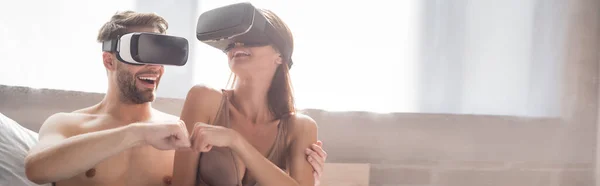 Sexy couple making fist bump while using vr headsets in bedroom, banner — Stock Photo